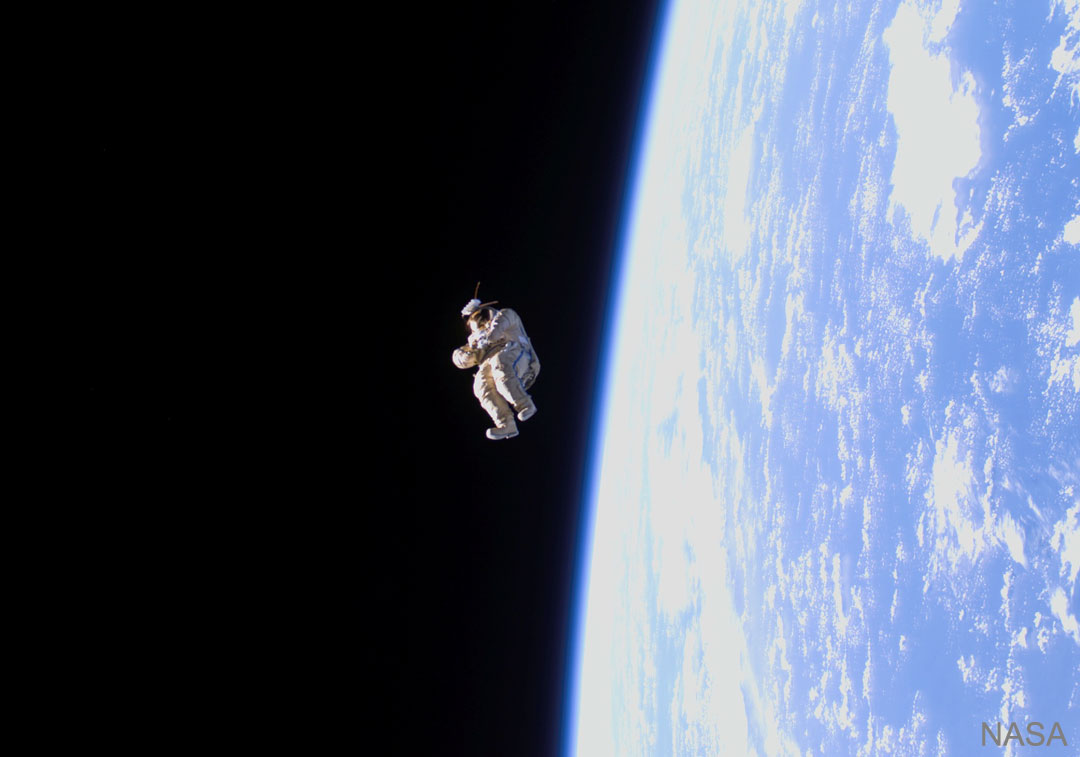 A spacesuit is shown floating high above the Earth. See Explanation.