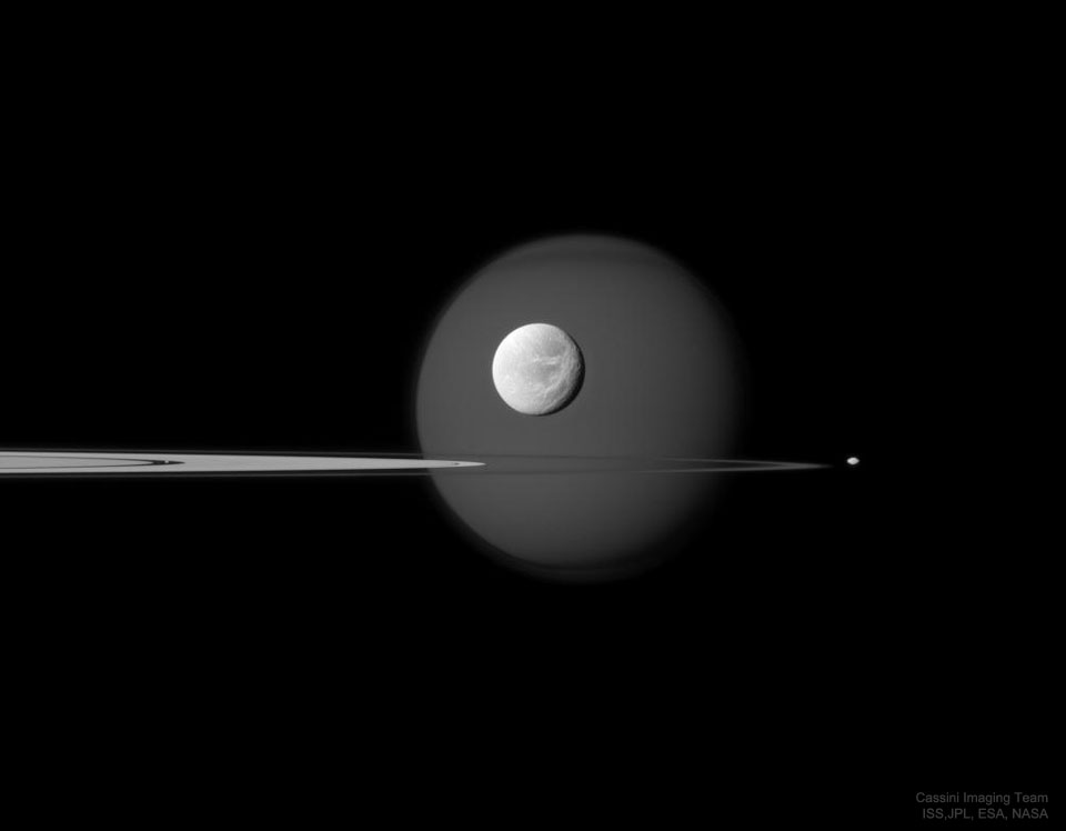 Pierścienie Saturna, widoczne niemal dokładnie z boku, oraz jego cztery księżyce. Zobacz opis.