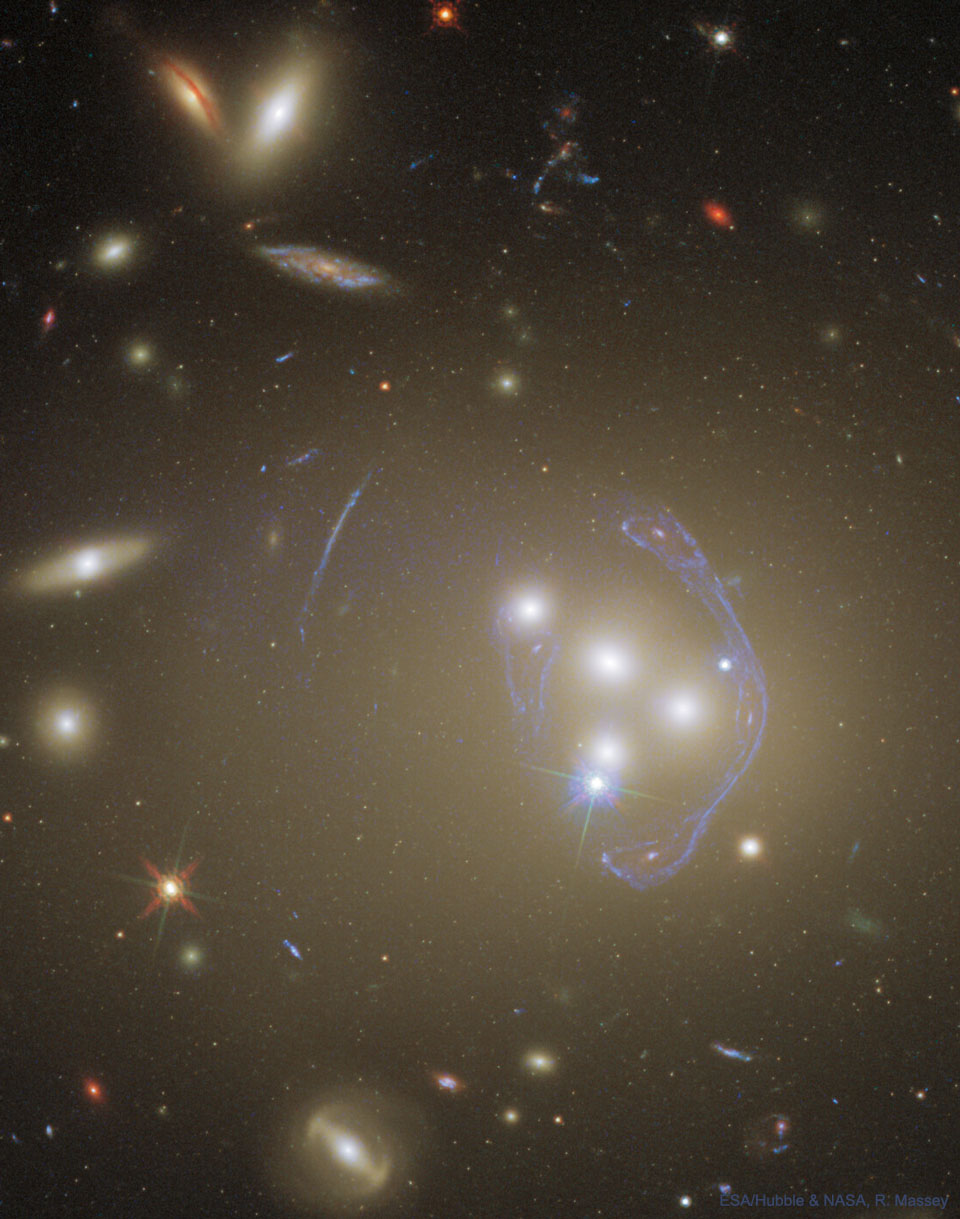 Zdjęcie przedstawia gromadę galaktyk Abell 3827 sfotografowaną przez Teleskop Hubble'a. Widoczne są łączące się galaktyki oraz złożony obraz 
galaktyki tła, powstały w wyniku oddziaływania gromady jako soczewka grawitacyjna. Więcej szczegółowych informacji w opisie poniżej.