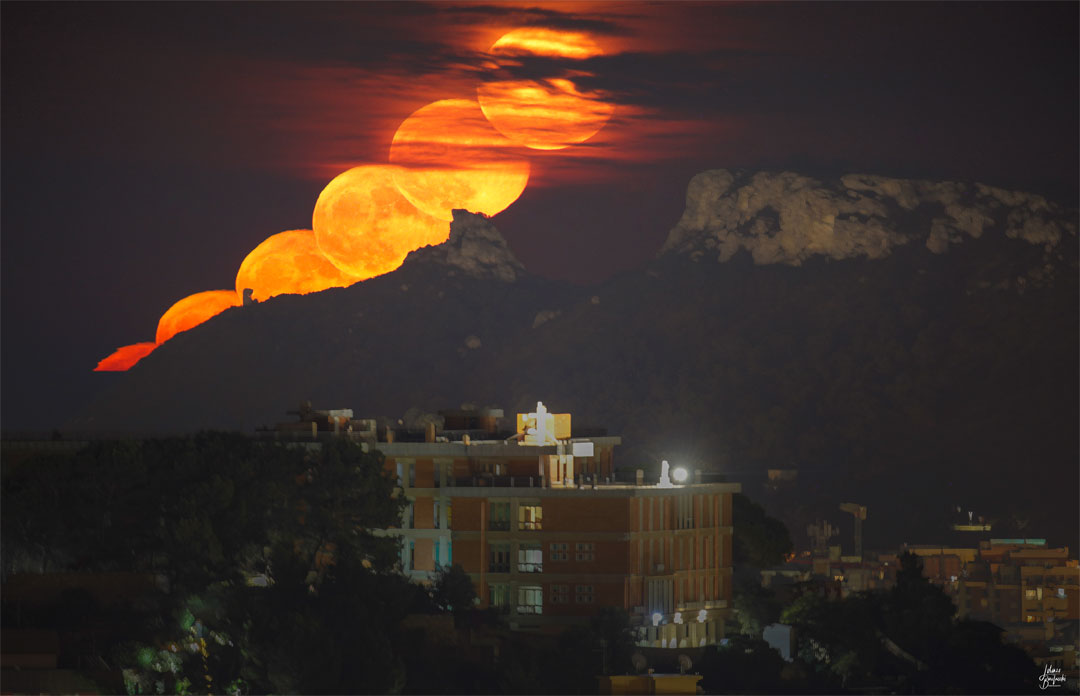 Prezentowane zdjęcie przedstawia pomarańczowy księżyc, wschodzący nad malowniczymi górami.
Więcej szczegółowych informacji w opisie poniżej.