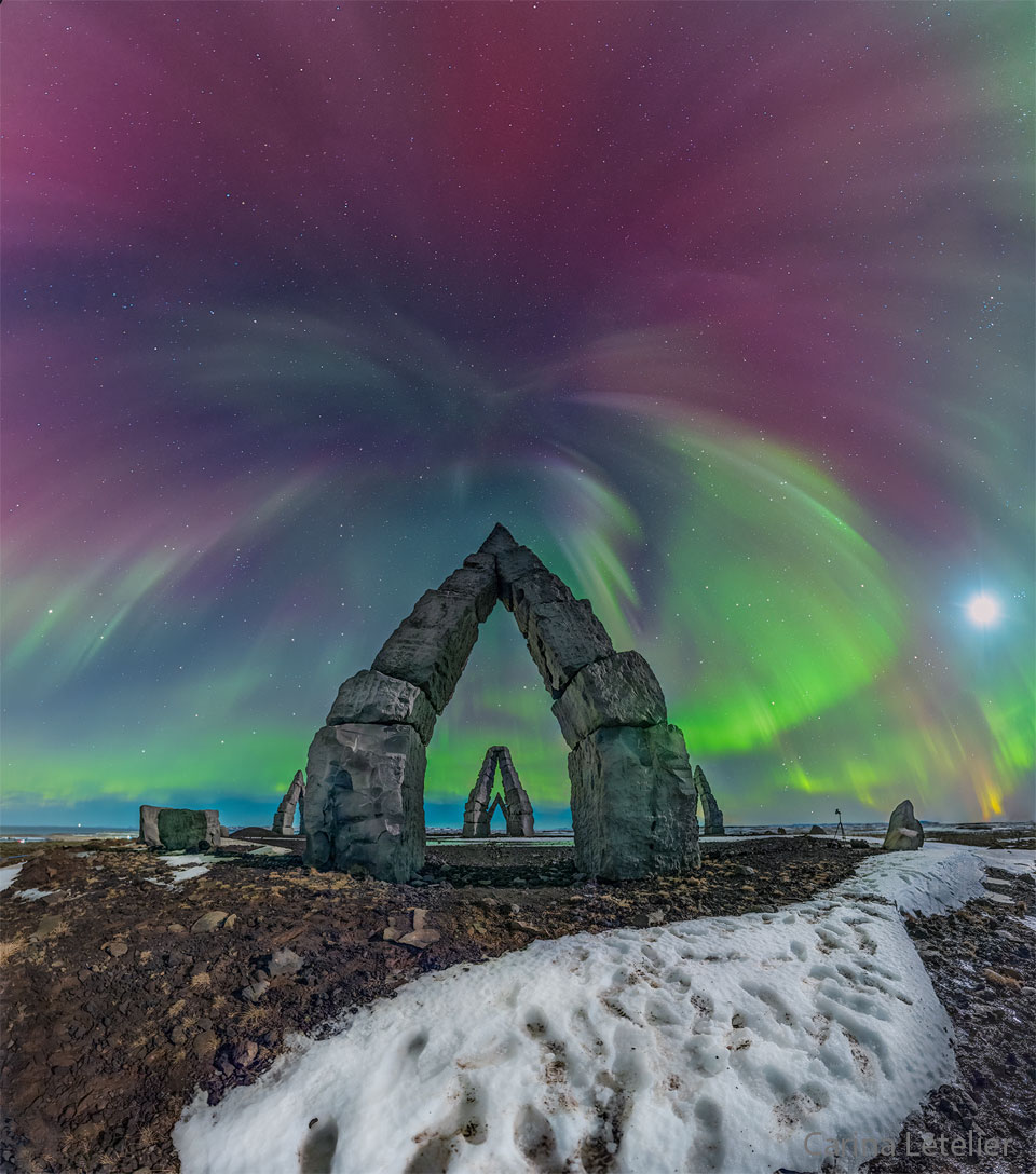 Multi-colored aurora are seen above an unusual stone
gateway, the first of several similar gateways seen in
the distance. 
Please see the explanation for more detailed information.