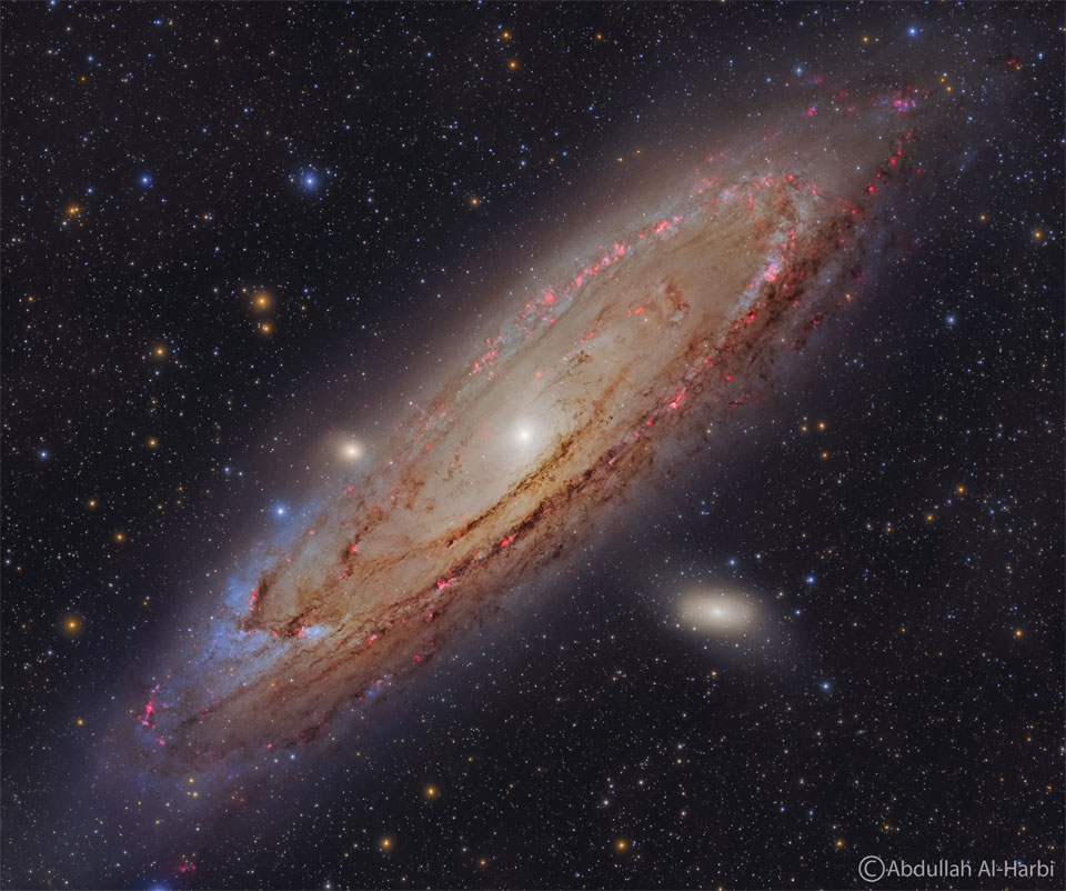 Galaktyka Andromedy widoczna jest bardzo szczegółowo. Czerwone mgławice, niebieskie gwiazdy oraz ciemny pył wirują wokół jasnego centrum Galaktyki.
Więcej szczegółowych informacji w opisie poniżej.