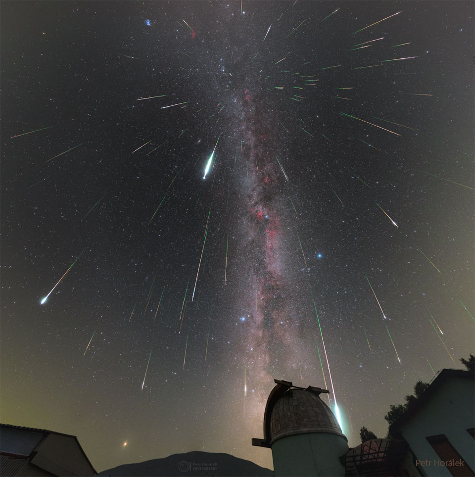 Mulitple streaks cover a night sky filled with stars.
An observtory dome is visible in the foreground. 
Więcej szczegółowych informacji w opisie poniżej.