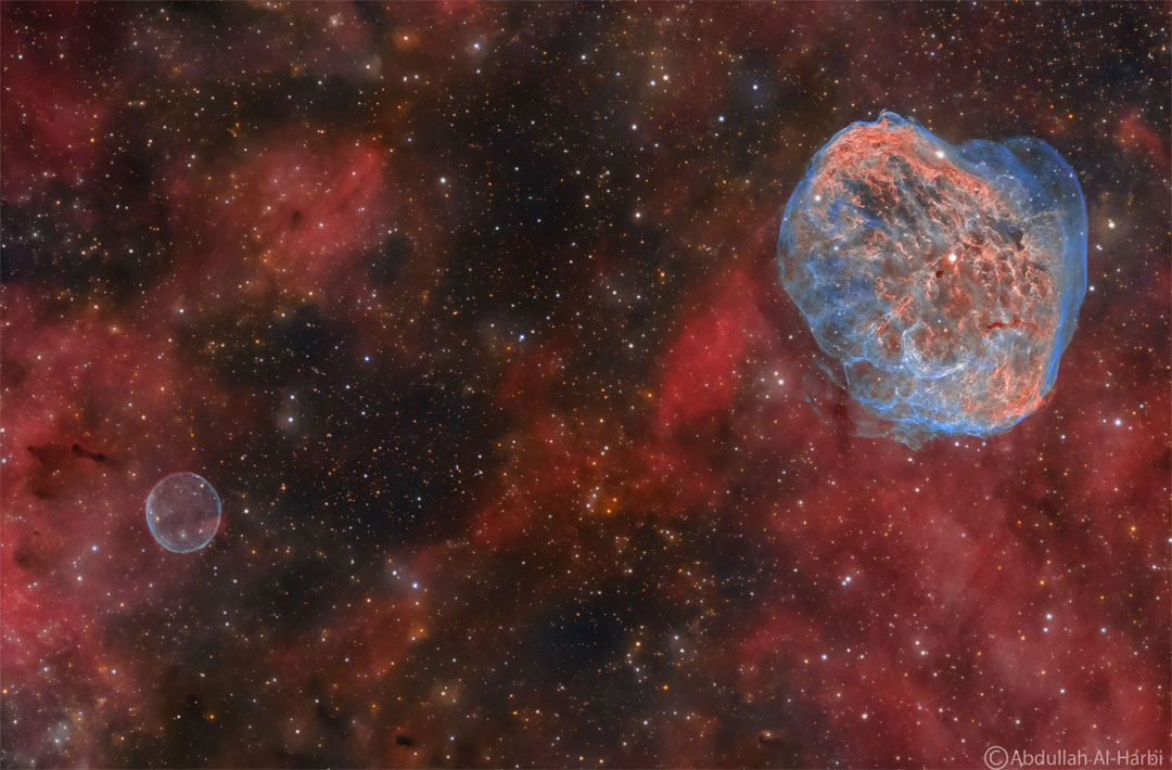 Na zdjęciu przed ciemnym polem gwiazd widoczny jest świecący
na czerwono gaz. Na górze po prawej natomiast widoczne są
zawiłe włókna mgławicowe w czerwieni i błękicie. Na dole po lewej
zaś znajduje się prosta sferyczna niebieska mgławica.
Zobacz opis. Po kliknięciu obrazka załaduje się wersja o największej
dostępnej rozdzielczości.
