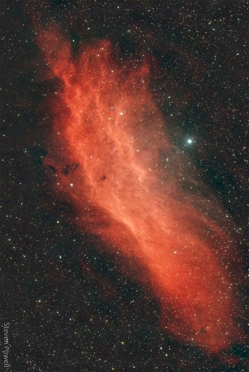 A red gaseous nebula is shown in front of a dark starfield.
The shape of the nebula resembles the US state of California.
Więcej szczegółowych informacji w opisie poniżej.