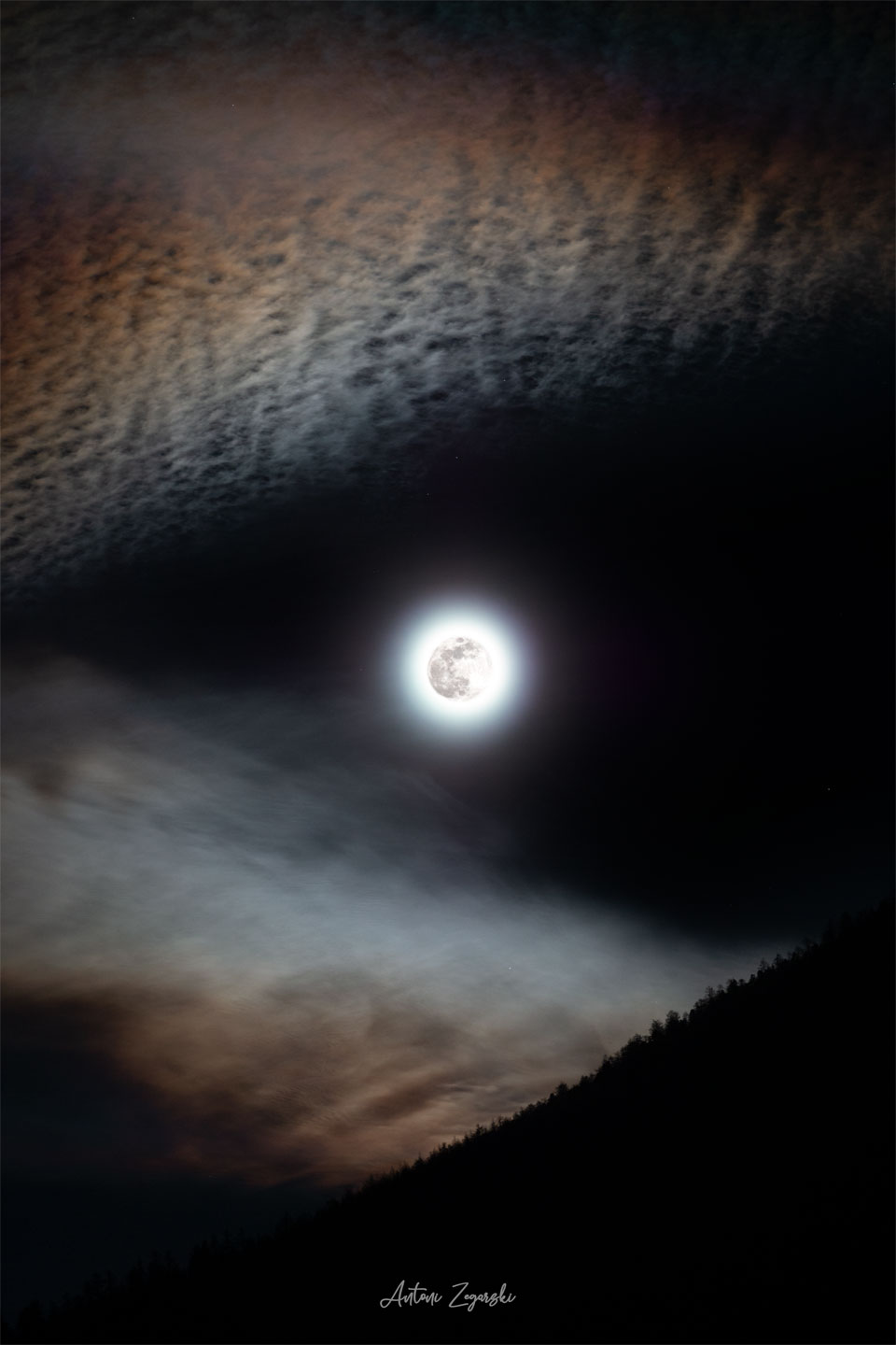 W centrum zdjęcia widoczny jest jasny Księżyc w pełni.
Wokół jego krawędzi znajdują się kanciaste chmury, przez które
Księżyc wyglądają, jakby tworzyły oczy lub pysk wilka.
Zobacz opis. Po kliknięciu obrazka załaduje się wersja
o największej dostępnej rozdzielczości.