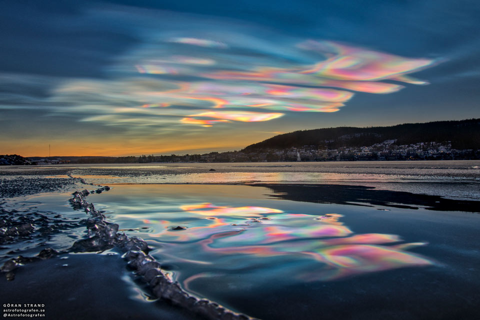 A landscape shows the sky above, shallow water in front,
and hills to the right. The sunset sky is filled with
beautifully multicolored clouds. These clouds are clearly
reflected by the calm water in front. 
Więcej szczegółowych informacji w opisie poniżej.