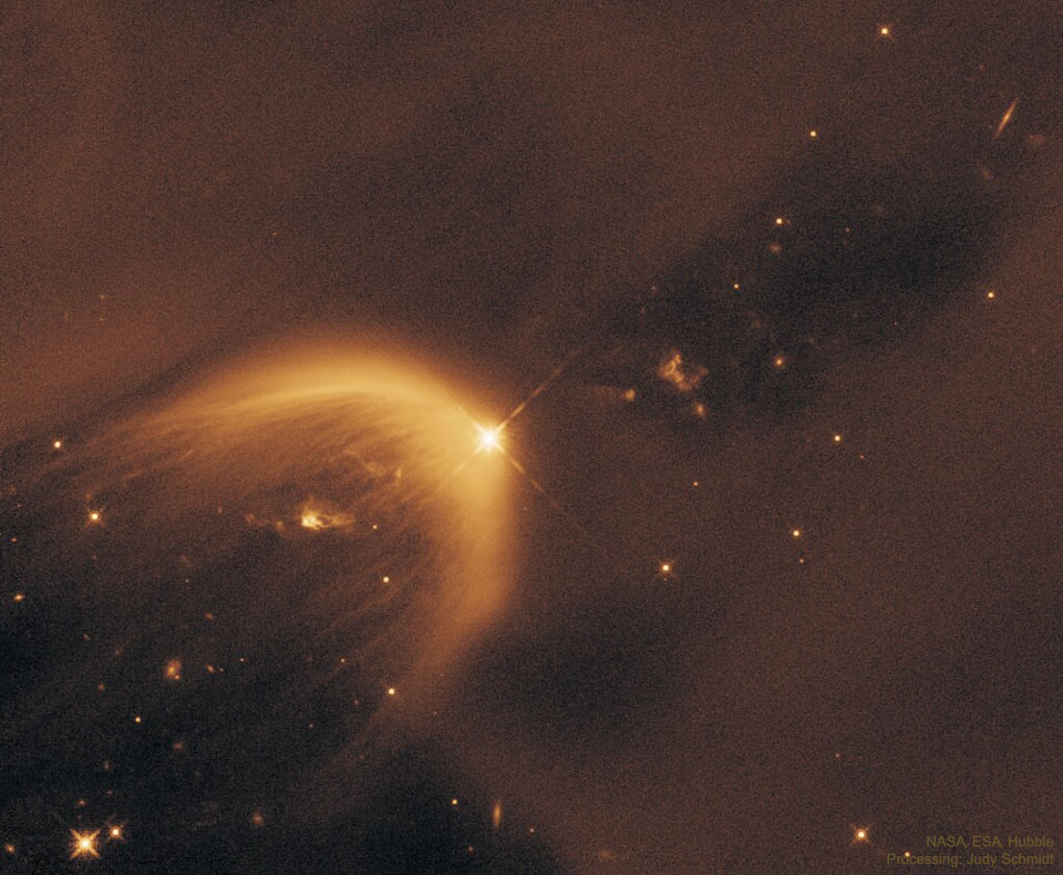 A starfield is dominated by light brown dust. In the 
middle is a parabolic gas cloud opening toward the lower right.
A bright star is near the center at the apex of the parabolic
gas cloud. 
Więcej szczegółowych informacji w opisie poniżej.