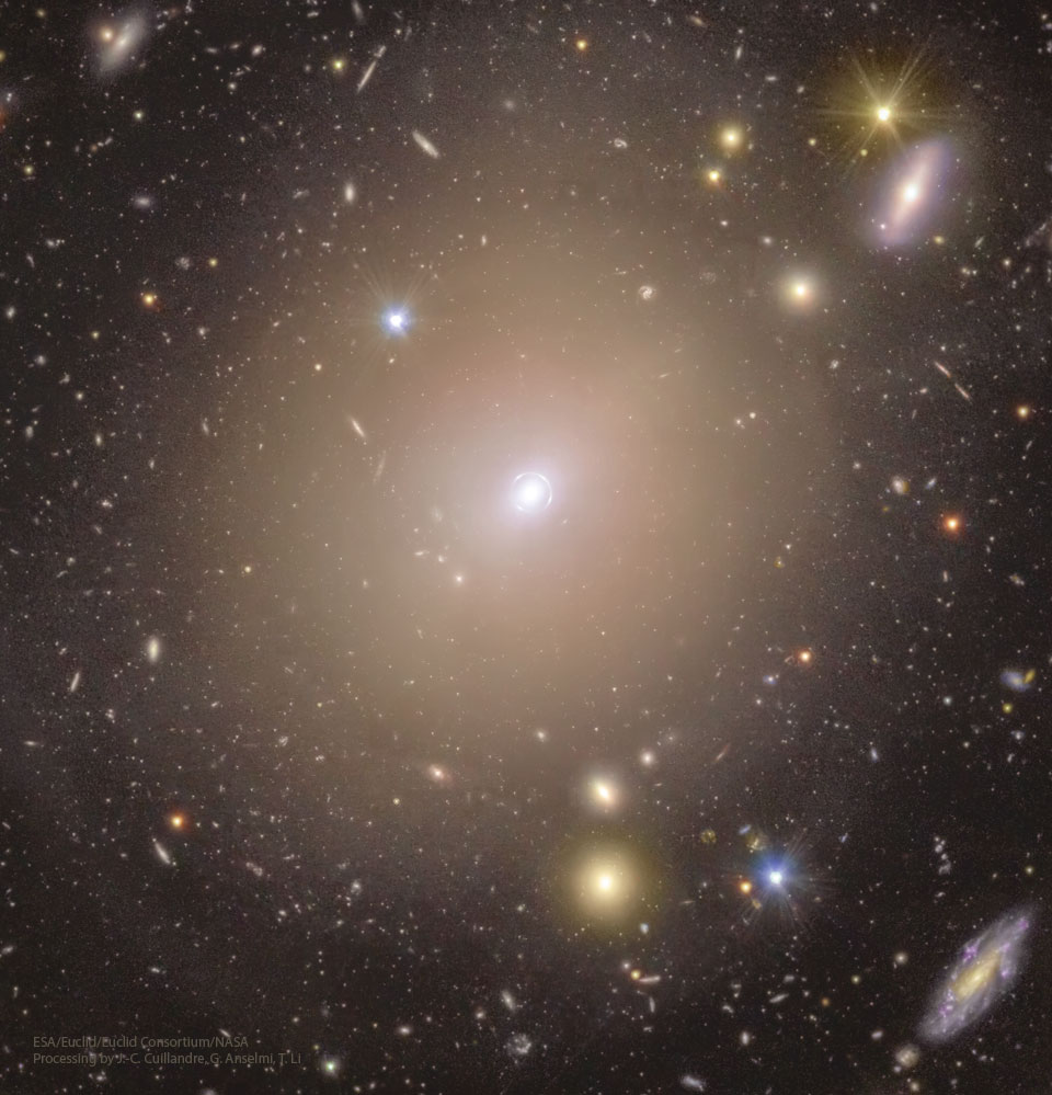 A cluster of galaxies is shown with many galaxies
around the cluster center. A close look at this center
shows that it is encompassed by a narrow ring of light.
Więcej szczegółowych informacji w opisie poniżej.