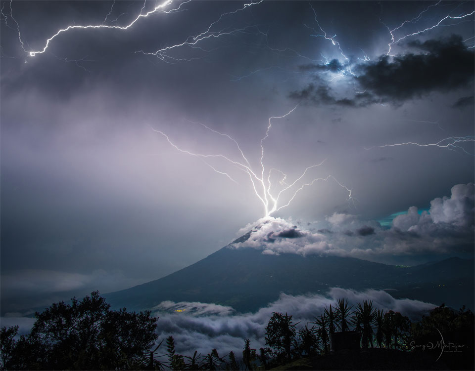 A volcano is shown with its peak in the midst of 
purple clouds. Lightning appears to come out of the 
top of the volcano in multiple paths into the upper sky.
Więcej szczegółowych informacji w opisie poniżej.