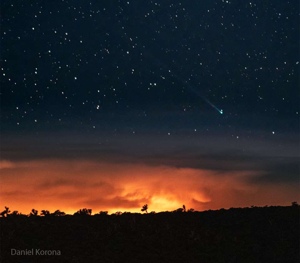 A starfield is seen above a horizon and an
orange sunset. In the starfield, near the horizon,
is a comet with a green head and long tail.
Więcej szczegółowych informacji w opisie poniżej.
