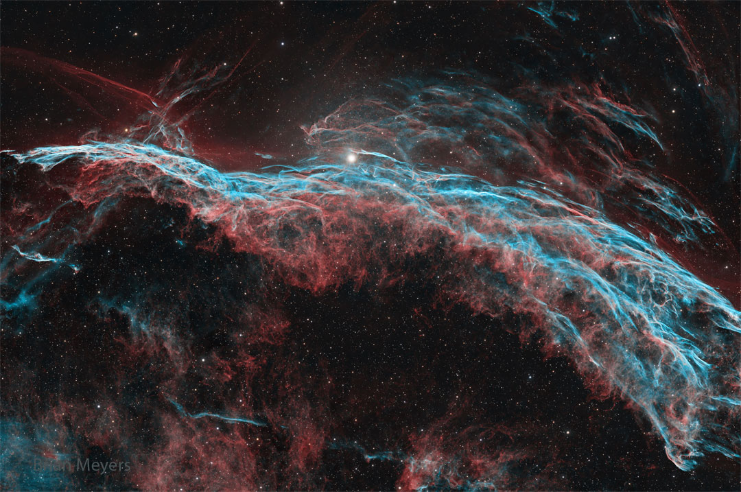 A starfield is shown that has a multi-filament
nebula flowing across it horizontally. The most 
prominent colors are red and blue. 
Więcej szczegółowych informacji w opisie poniżej.