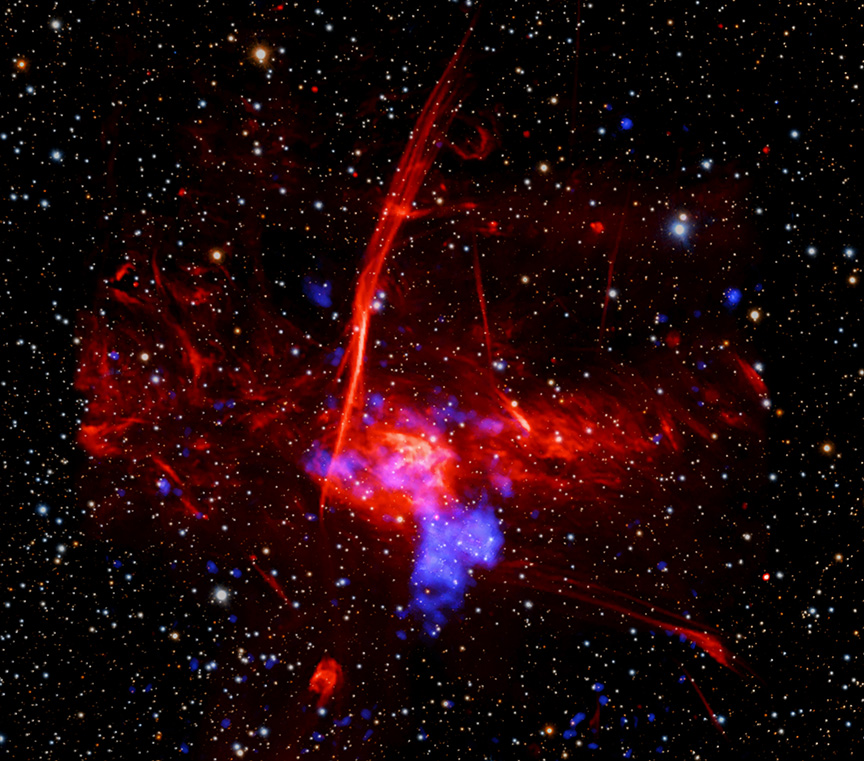 A composite image shows a field of stars on a dark background,
	  together X-rays in blue and radio in red